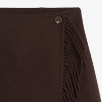 Close-up of a dark brown woolen wrap or scarf with fringe trim and a small dark button detail, shown against a plain white background.