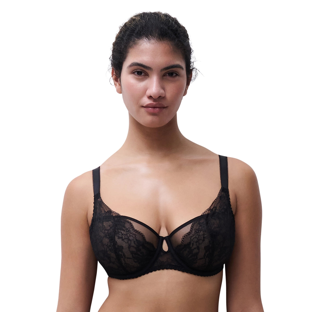A woman modeling a black lace underwire bra against a solid white background.