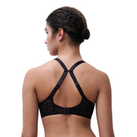 A woman shown from the back wearing a black lace bra with crisscross shoulder straps and adjustable back bands, photographed against a plain white studio background.