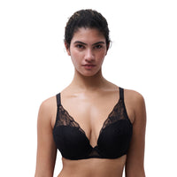 A woman modeling a black lace-trimmed underwire bra against a plain white background.