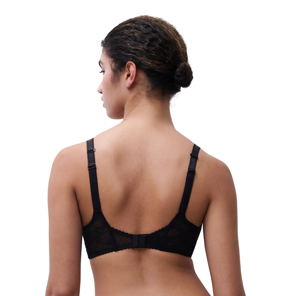 A woman shown from the back wearing a black lace bra with adjustable shoulder straps and a ruffled underband, against a plain white background.
