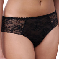 Black lace panties worn by a model, showing the floral lace pattern and scalloped waistband against a plain white background.