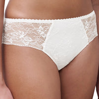 White lace bikini briefs on a model, featuring a solid white center panel and intricate floral lace side panels with a scalloped waistband.