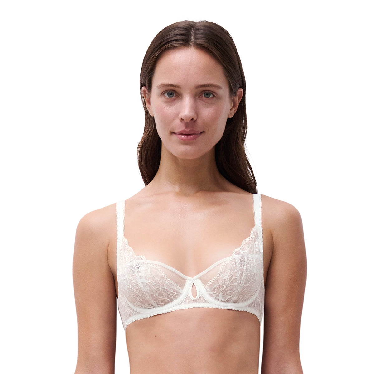 A woman modeling a white lace underwire bra against a solid white background.