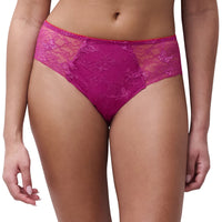 A close-up of a model wearing bright magenta lace panties against a plain white background.