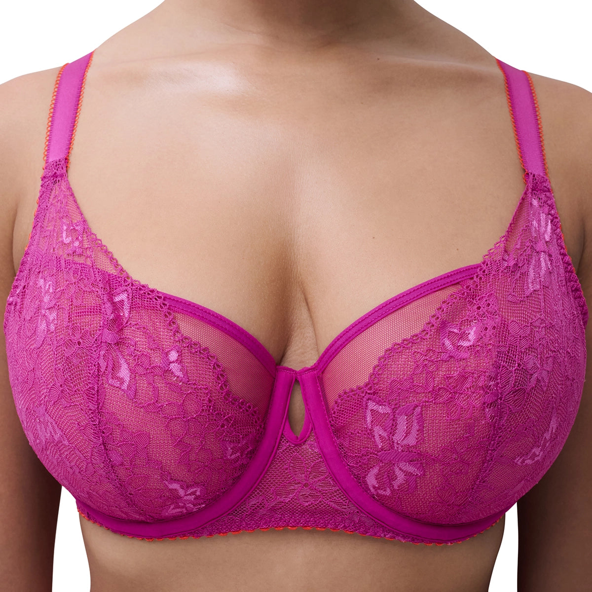 A close-up of a model wearing a bright pink lace bra with butterfly patterns and matching underwire cups.