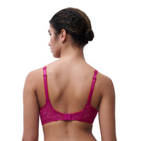 A woman shown from the back wearing a bright magenta lace bra with adjustable shoulder straps and a center gore, photographed against a plain white studio background.