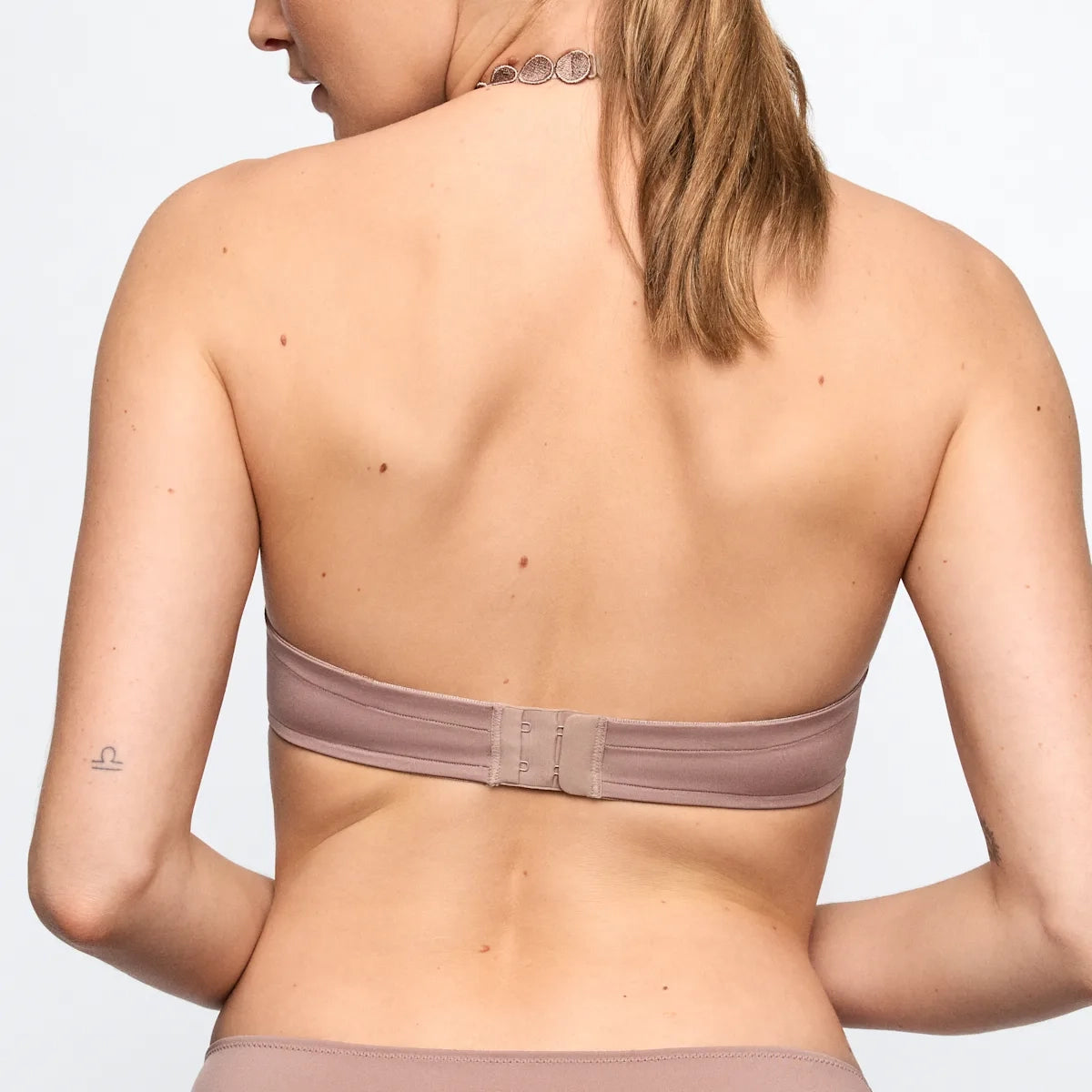 Person wearing a strapless bra with a plain background
