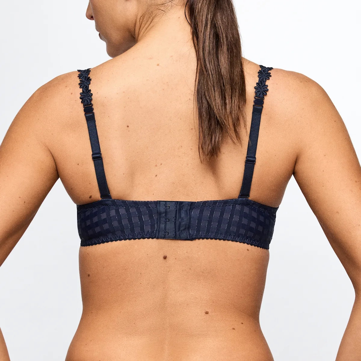 Navy blue bikini top worn by a person on a light gray background