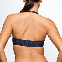 Navy blue bikini top worn by a person on a light gray background