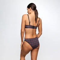 A woman shown from the back wearing a two-piece plaid lingerie set in dark gray, black, and pink, against a plain light gray studio background.