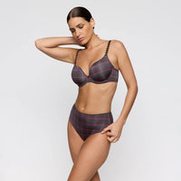 A woman modeling a lingerie set with a dark grey and red tartan plaid pattern, featuring bralette cups with braided straps and high-waisted bottoms, against a light grey studio background.