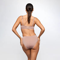 A woman shown from the back wearing a matching nude-beige bra and high-waisted brief set against a light gray studio background.