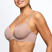 A close-up of a woman wearing a seamless underwire bra in a dusty rose color, featuring decorative silver-tone oval embellishments along the upper straps.