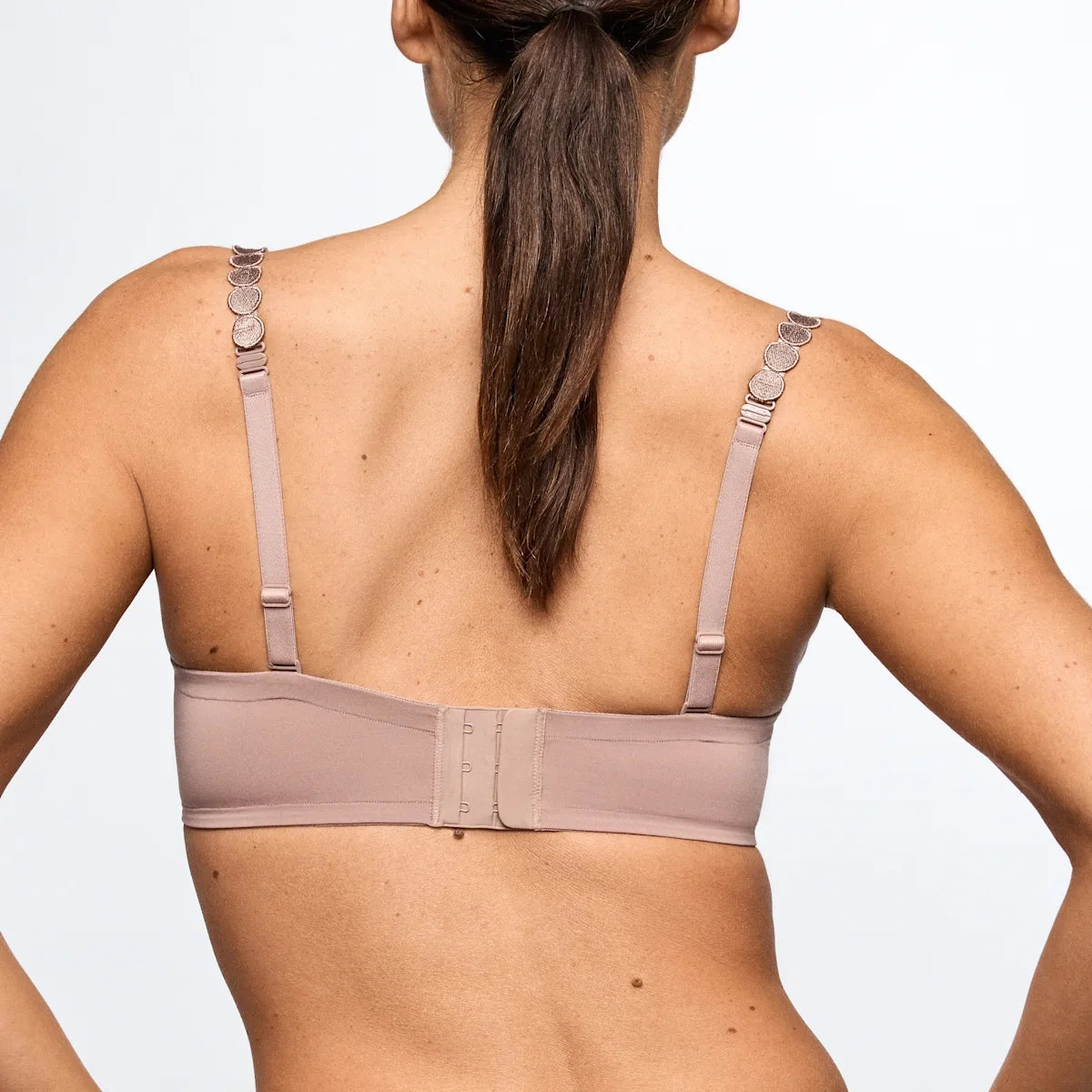 Woman wearing a beige bra against a plain background
