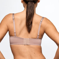 Woman wearing a beige bra against a plain background