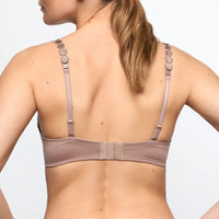 Rear view of a woman wearing a dusty mauve bra with decorative round metal discs along the upper straps, set against a plain white background.