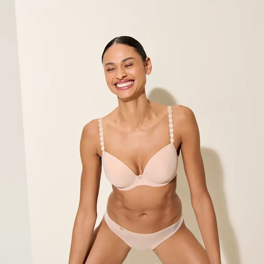 woman wearing a beige bra and panties set against a plain background