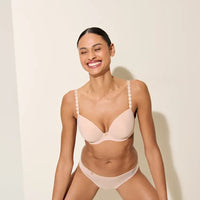 woman wearing a beige bra and panties set against a plain background
